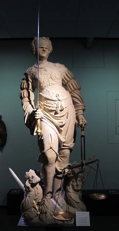 Photographie d’archive de la version précédente : statue de pierre de la Justice, les yeux bandés, le glaive levé, la balance à la main.