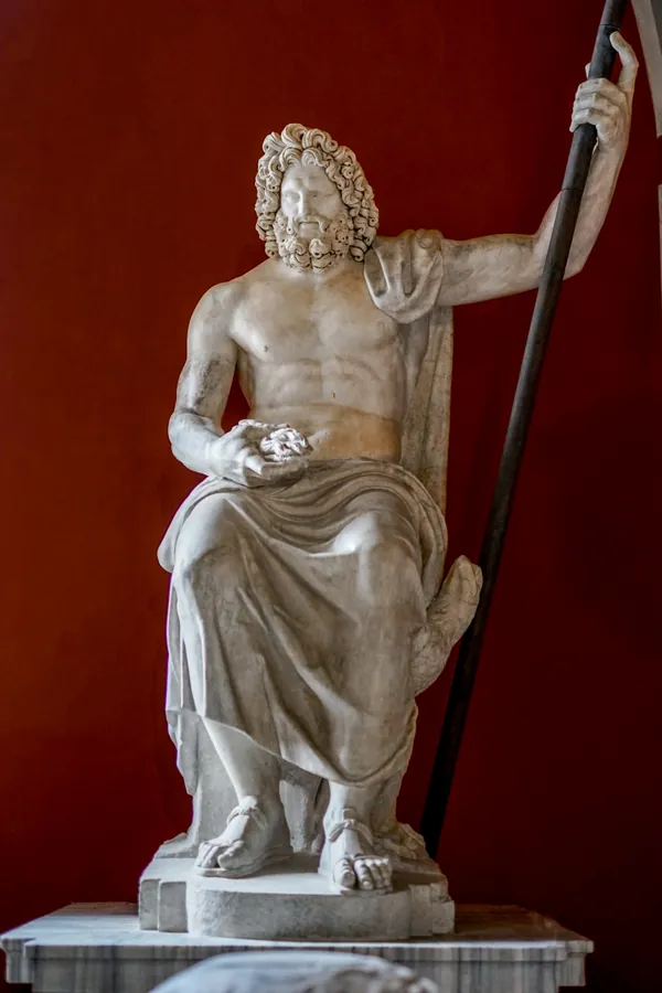 Photographie d’archive de la version précédente : statue de marbre de Jupiter assis, torse nu, drapé sur les jambes, le bras levé tenant un sceptre.